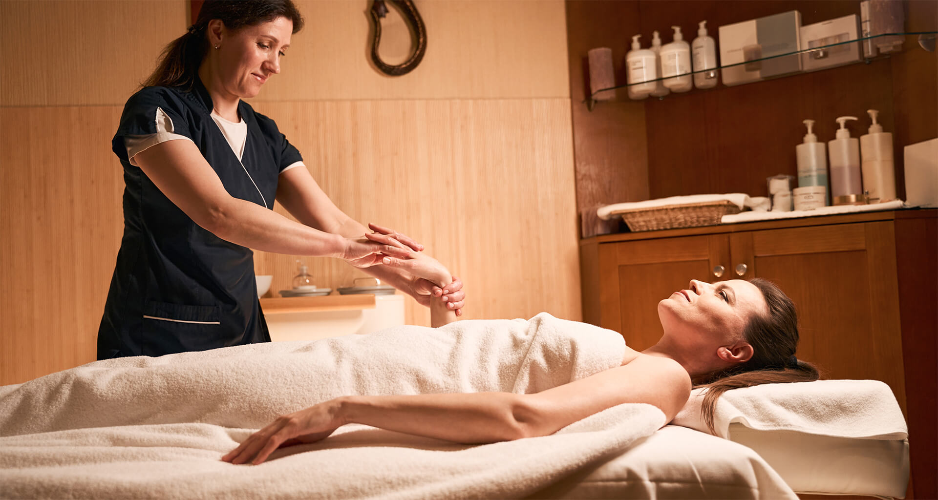 Massothérapeute massant l’avant-bras d’une cliente allongée sur une table de massage