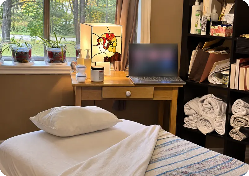 Salle de massage G3n à Saint-Jérôme : table de massage, lampe en vitrail et étagère de serviettes