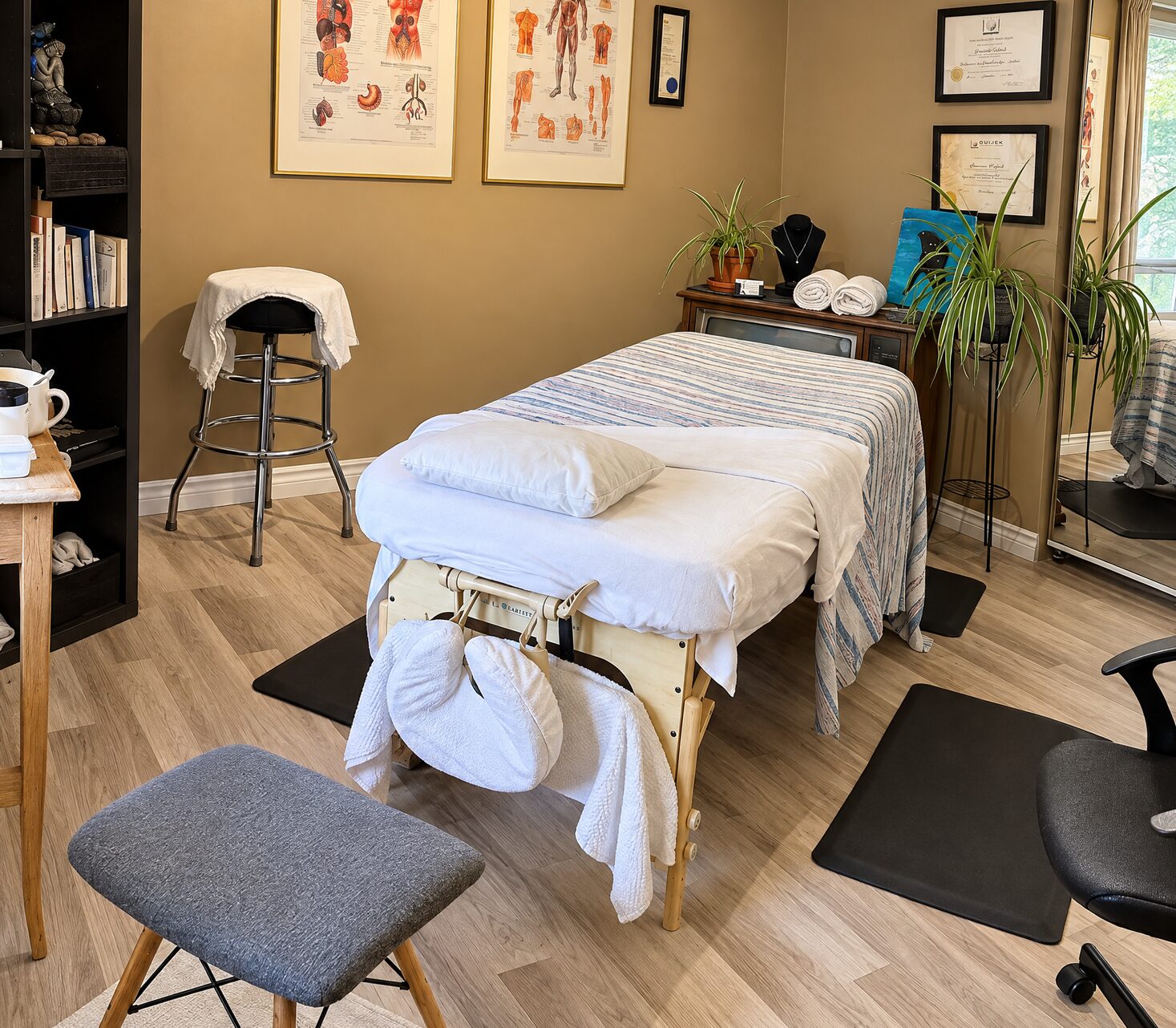 Salle de massothérapie de G3n à Saint-Jérôme : table de massage, tabouret et planches d’anatomie au mur